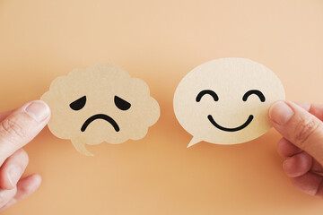 Hands holding happy and sad face on speech bubble paper, World mental health day, Psychology and speech therapy concept