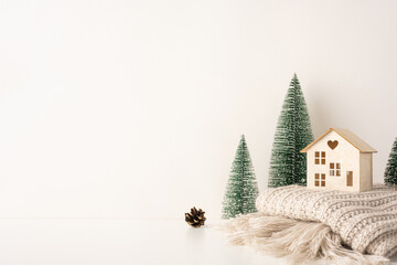 Minimalist side view Scandinavian Christmas scene with a wooden house, pine trees, and knit blanket capturing cozy and serene winter vibes