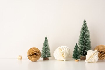 A side view simple Scandinavian-inspired Christmas arrangement featuring miniature pine trees and geometric paper ornaments. The image showcases an elegant and minimalist holiday decor setting. © ActionGP