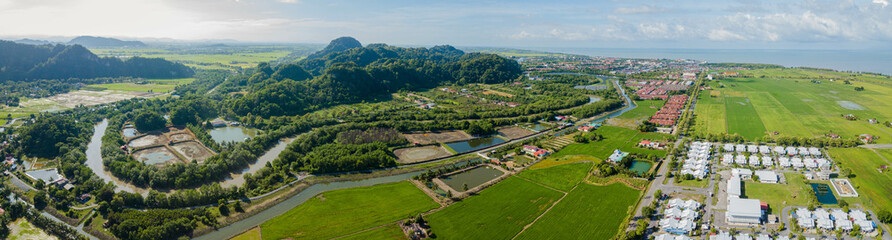 Panoramic aerial drone view of residential area near green paddy crops land at Kampung Wai, Perlis, Malaysia