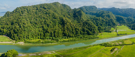 Breathtaking aerial drone view of waterway canal near green paddy crops land at Kampung Wai,...