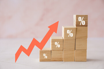 Wooden blocks with percentage sign and arrow up, financial growth, interest rate increase,...