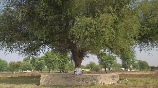 young Indian yogi doing his yoga mediation practices on hills rocks in forest