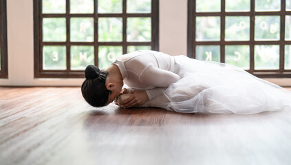 Asian girl ballet dancer gymnastic exercises in studio for body flexibility Ballerina training stretches her leg and prepares for performance practice routine.
