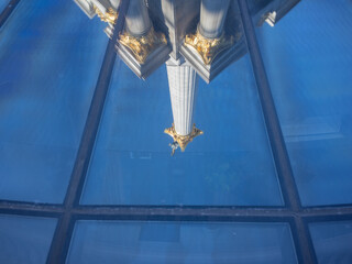 blue sky and tall monument of independence square reflected on the glass window in winter kyiv