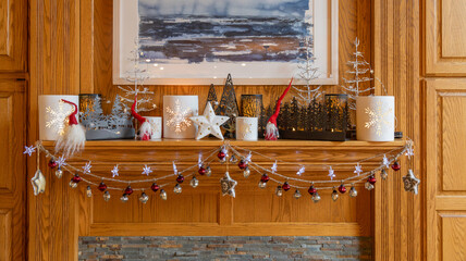 Fireplace mantel shelf decorated with an assortment of various beautiful Christmas ornaments, trees...