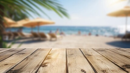 Wooden planks in the foreground with a sunlit beach and ocean blurred in the background, featuring umbrellas and beachgoers under a clear sky.