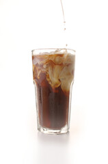Pouring fresh milk into iced coffee on a white background
