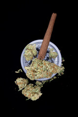 Medical cannabis buds are dried flowers used for therapeutic benefits, rich in THC, CBD, and terpenes. presented with prerolled joint and grinder against black background