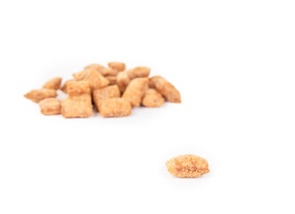 Cat treat with defocused pile. Heap of dry chicken treat or snack for cats or dogs. Used for rewards, training or obedience. Yellow brown crunchy dry pet food. Selective focus. White background.
