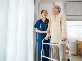 Asian nurse and her senior old man client on walking frame medical healthcare tools looking out of...