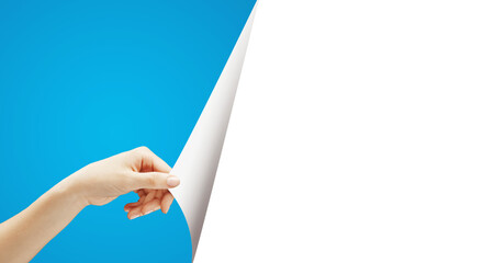 A hand peeling back a white page to reveal blue underneath, on a blue and white background. Concept...