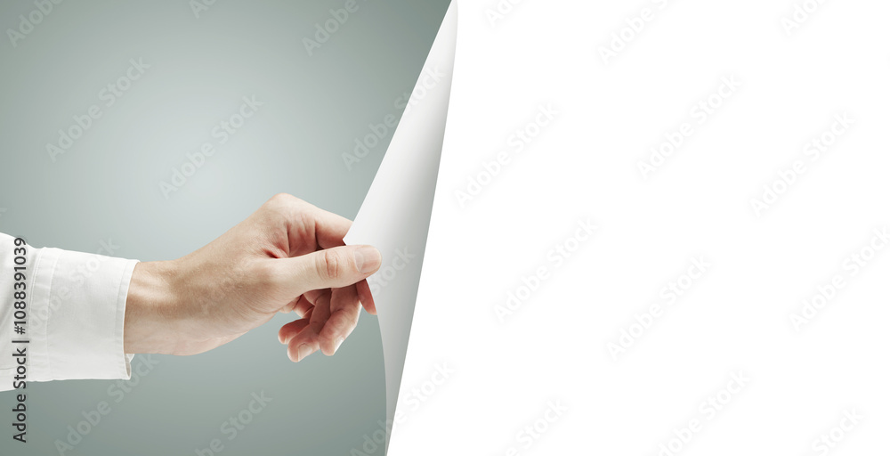 Aufkleber a hand holding and peeling back a blank sheet of paper, revealing empty white space. set against a s