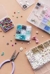 Crafting with colorful beads on a flat workspace with tools and containers in bright daylight