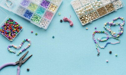 Colorful assortment of beads and jewelry-making tools on a blue surface with completed bracelets