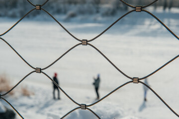 people behind a mesh fence in winter
