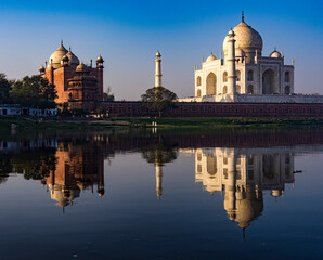 The iconic taj mahal and its mirror image on the yamuna river during a tranquil sunrise