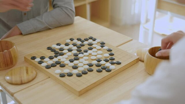Close up of young men play board game Go during competition in community. 