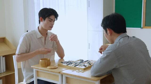 Asian young men playing board game Go during competition in community. 
