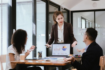 A diverse team of young professionals work together in a modern office to brainstorm creative ideas for a startup project. Coworkers work together on laptops in a casual atmosphere.