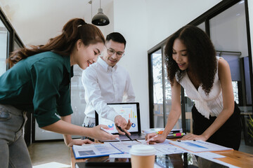 A diverse team of young professionals work together in a modern office to brainstorm creative ideas for a startup project. Coworkers work together on laptops in a casual atmosphere.