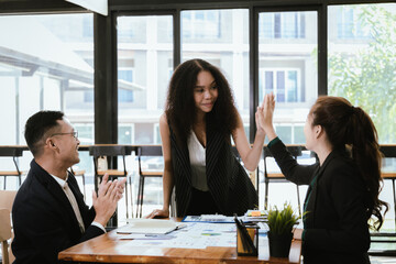 Asian and Caucasian corporate executives discuss business in a conference room of three young businessmen and women discussing tech startups