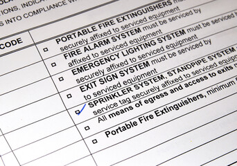 Fototapeta premium Notice of violation for sprinkler system failure issued by fire department. Check mark on sprinkler. Ticket or fine for non-compliance of fire code or fire equipment system problems. Selective focus.