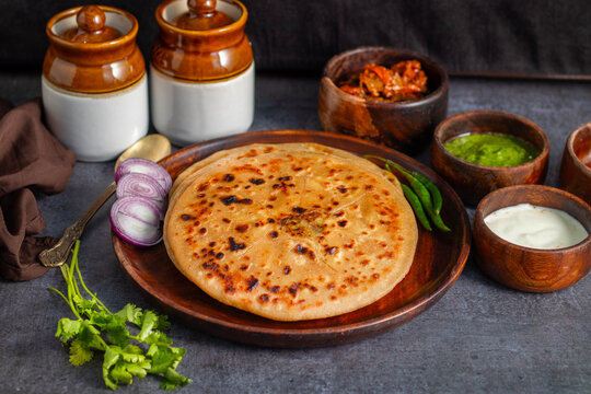 Aloo paratha, a North Indian delight from Punjab, Uttar Pradesh, and Bihar, is a stuffed flatbread served with tangy achar and creamy butter.