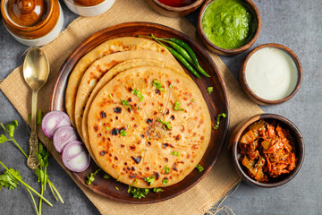 Aloo paratha, a flavorful Indian flatbread stuffed with spiced mashed potatoes, served hot with tangy pickle (achar) and refreshing chutney, creating a perfect balance of zest and warmth.