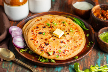 Aloo paratha, a popular North Indian dish from Punjab, Uttar Pradesh, and Bihar, is a stuffed flatbread filled with spiced potatoes, served hot with butter and tangy pickle.