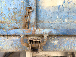 A rusty chain is attached to a blue door