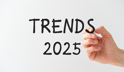 The hand of a business woman with a pen in her hands writes on a transparent background Trends 2025, Business Concept.