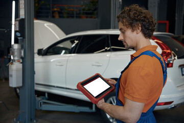 Portrait of male car technician looking at computer