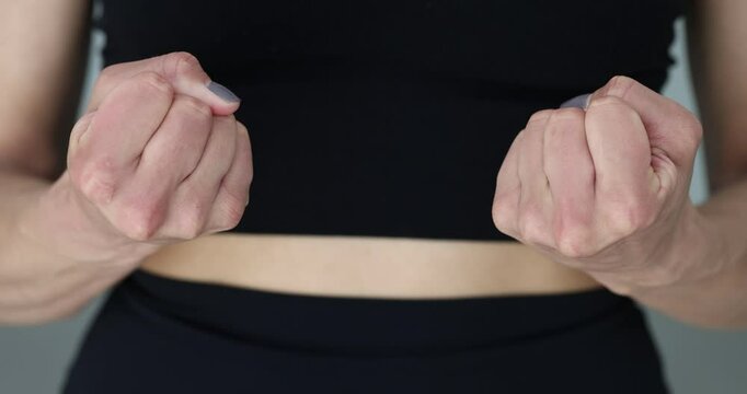 Woman shows empty hands and clenches fists
