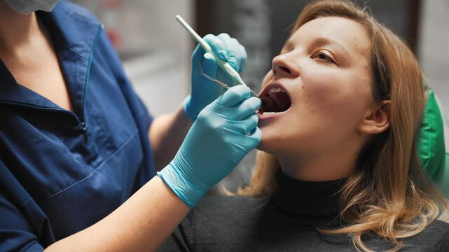 Healthcare and medicine, young woman visiting dental clinic, closeup view. Professional doctor examining oral cavity of female patient, dental filling, implantation and curing caries, healthcare