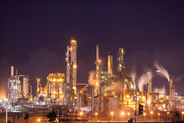 Fototapeta premium Night time view of a refinery spewing toxic CO2 Carbon Dioxide greenhouse gases that cause global warming.