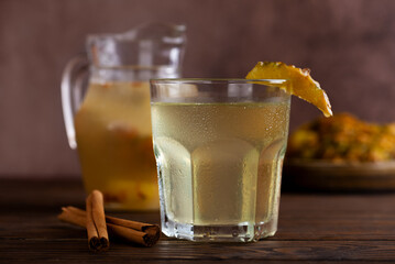 Fermented pineapple drink or fruits kvass with natural juice and cinnamon in glass on a wooden table. Refreshing pineapple cocktail.