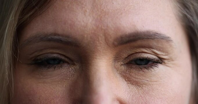 Closeup of woman blue eyes blinking while looking directly at camera