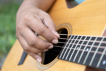 Guitar player strums the acoustic instrument, their fingers moving skillfully to create a melody...