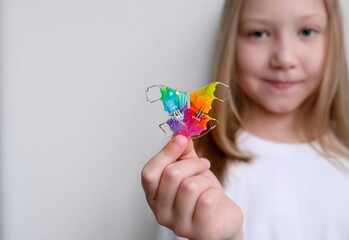 A dental plate for children of rainbow color. The child holds orthodontic braces in his hands to align the teeth and expand the jaw.
