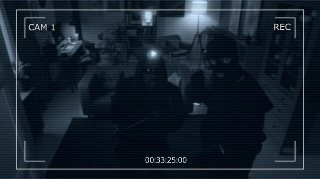 CCTV shot of two multi-ethnic male burglars with headlamp and flashlight paying attention to hidden camera while robbing apartment
