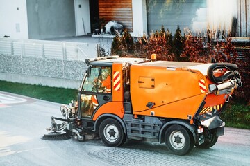 Street cleaning machine is sweeping and washing driveway and footway in suburban neighborhoods in...