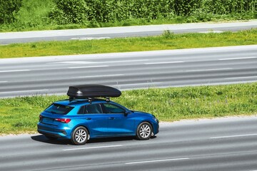 Car equipped with a rooftop cargo carrier amidst heavy traffic on a sunny day