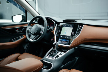 Modern brown car interior, leather steering wheel, climate control, large navigation screen, air...
