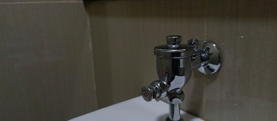 Close up urinal water dispenser, pushing button of flushing toilet.