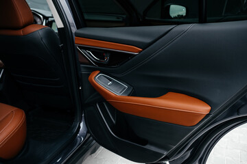 Modern brown car interior, leather steering wheel, climate control, large navigation screen, air ducts, deflectors on the car panel. Interior details.
