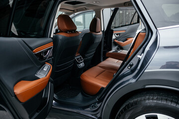 Modern brown car interior, leather steering wheel, climate control, large navigation screen, air ducts, deflectors on the car panel. Interior details.