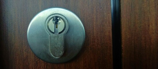 Fototapeta premium A close-up of a stainless steel keyhole set into a polished wooden door.