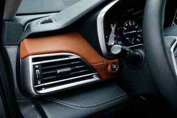 Modern brown car interior, leather steering wheel, climate control, large navigation screen, air...