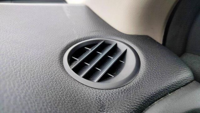 vents or air conditioning ducts in the car. Focus on the aircond hole on the dashboard of the vehicle. It is gray in color and the background is blurred